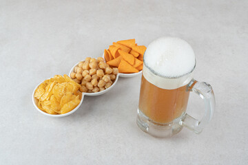 Snack bowls and glass of beer on stone surface