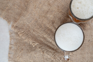 Two glasses of foamy beers on burlap