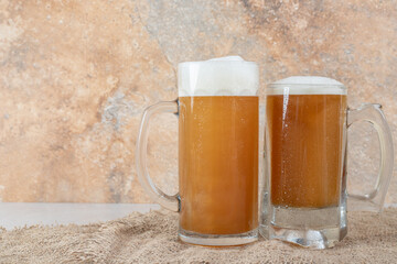 Two glasses of foamy beer on marble background