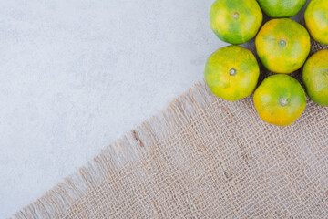 Several fresh sour whole tangerines on sackcloth