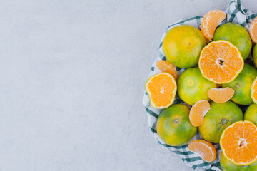 Sliced and whole tangerines in tablecloth on white background
