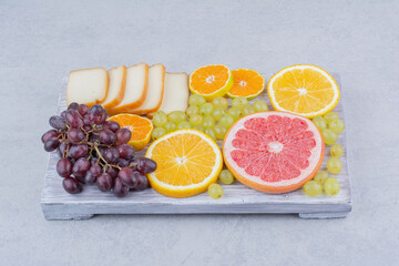 A wooden board full of sliced fruits and bread