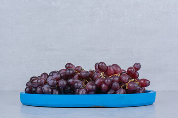 Fresh sweet grapes in blue plate on white background