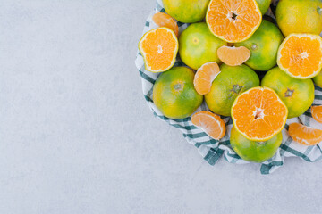 Sliced and whole tangerines in tablecloth on white background