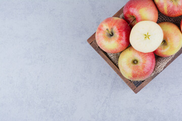 A wooden basket full of apples on white background