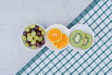 A white plates of fresh fruits on tablecloth