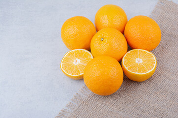 Fresh oranges lying on sackcloth on white background