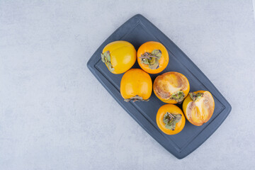 Several tasty persimmons on dark board