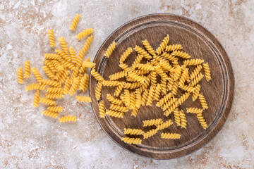 Tray of scattered raw pasta on marble background