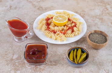 Delectable lunch set of macaroni with dressings, seasoning and topping on marble background