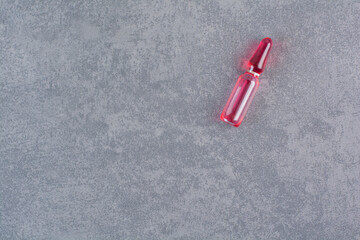 Red medical ampoule on marble background