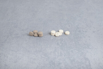 Fototapeta na wymiar A bunch of medicines from brown tablets and white capsules on a gray background
