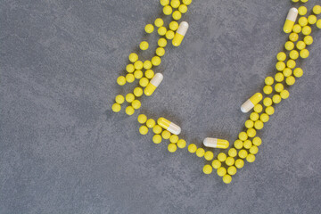 Yellow medical tablets and capsules on marble background