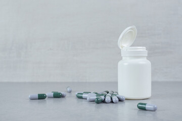 Fototapeta na wymiar A small white jar of pills on gray background