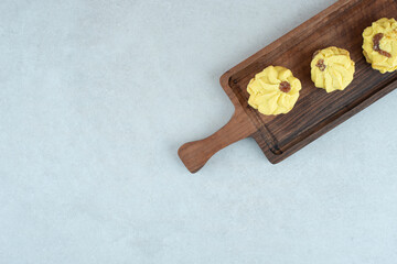 Fototapeta na wymiar A wooden cutting board with three delicious cookies on white background