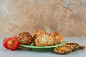 A green plate of round sweet cookies with dried oranges and Christmas balls