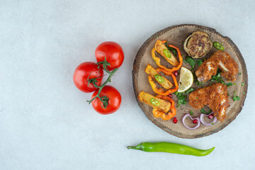 A wooden plate with peppers and tomatoes on white background
