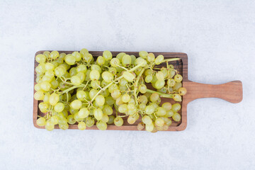A wooden board full of sweet grapes on white background
