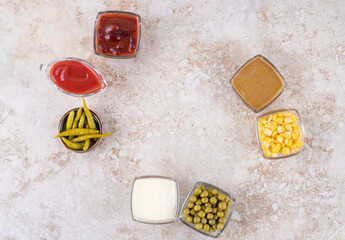 Portions of various dressings and toppings displayed on marble background