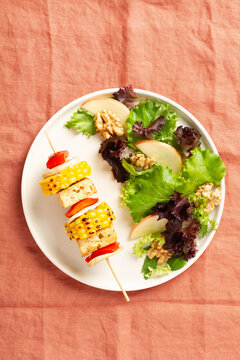 Vegan plate with vegetable skewer with tofu served and salad