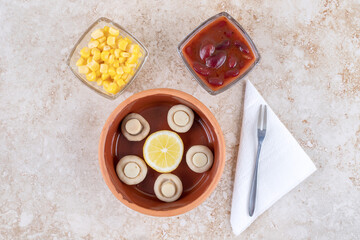 Bowls mushrooms, red sauce and corn kernels on marble background