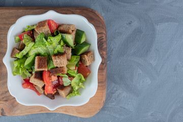 Shepherd's salad on wooden board on marble background