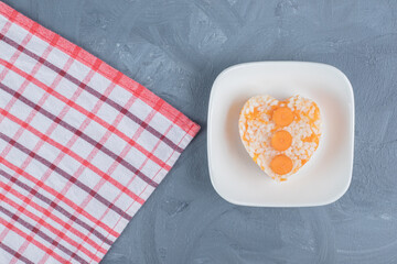 Small portion of cooked rice next to a towel on marble background