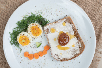 A white plate with toast and boiled eggs on sackcloth