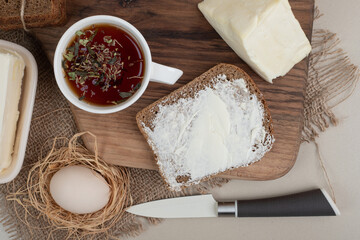 A wooden cutting board with toast and cup of tea on sackcloth