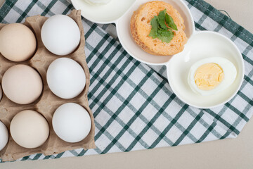 Fresh chicken white uncooked eggs with boiled egg on tablecloth