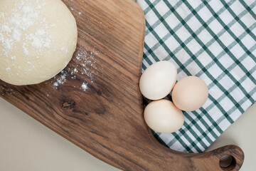 Dough with three chicken fresh white eggs on wooden cutting board