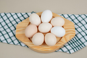 Several fresh chicken white eggs on wooden plate