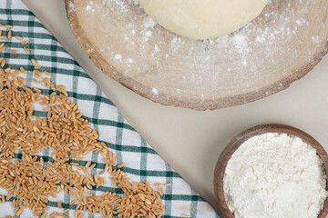 Dough with wooden bowl of flour on wooden board