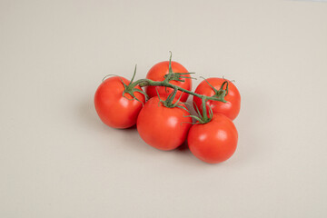 Bunch of fresh, red tomatoes with green stems on white background