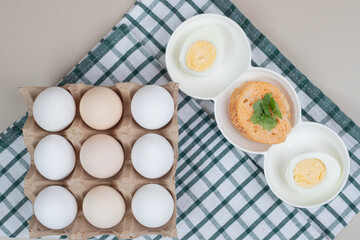 Fresh chicken white uncooked eggs with boiled egg on tablecloth