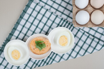Fresh chicken white uncooked eggs with boiled egg on tablecloth