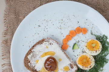 A white plate with toast and boiled eggs on sackcloth
