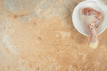 A white plate of chicken leg with spices