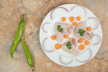 Uncooked chicken leg with chili peppers on marble background