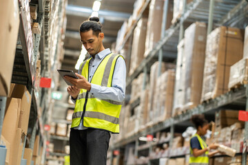 Asian man holding a tablet to check product quality and count the number of furniture on a shelf...