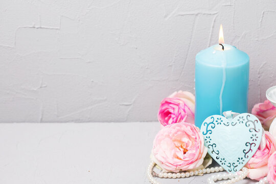 Summer   still life  greeting card. Decorative blue hert, canddle and tender  pink roses on grey textured background. Place for text.