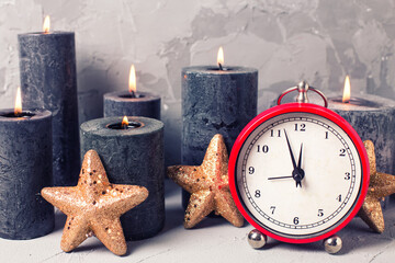 Fototapeta na wymiar Winter holiday, Christmas, New Year greeting card. Clock, stars and burning candles on grey textured background. 