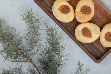 Sweet cookies with jam on wooden cutting board
