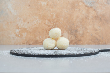 A dark cutting board with round pastry with powdered sugar