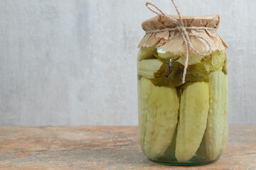 A jar of homemade pickled cucumbers on marble table