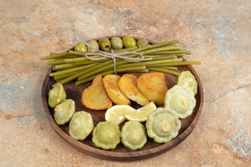 Pickled olives, green beans and fried potatoes on wooden plate