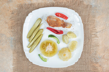 Chicken leg with various pickles on white plate