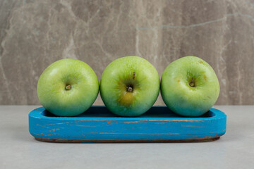 Fresh green apples on blue plate