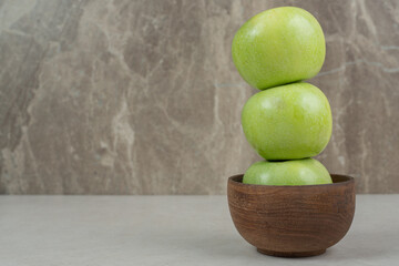 Whole green apples in wooden bowl