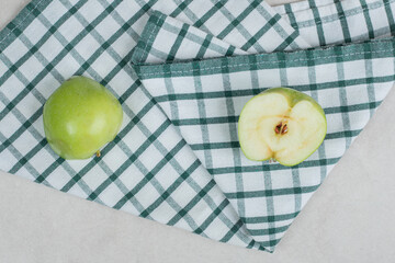 Whole and half cut green apples on tablecloth